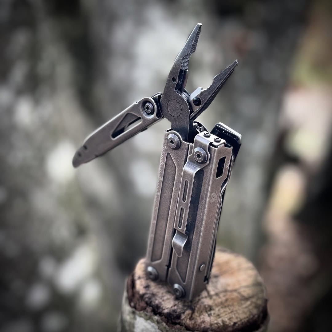 Stainless steel multi-tool with pliers open on wooden stump