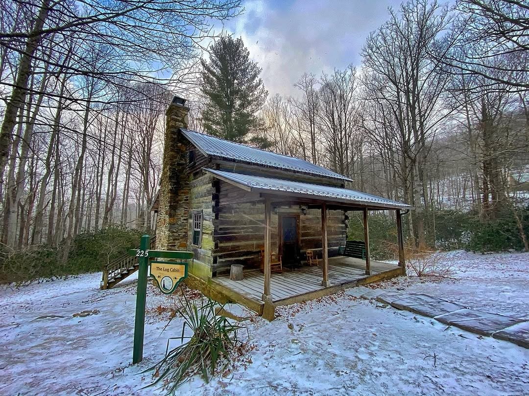 Snow-covered log cabin in woods