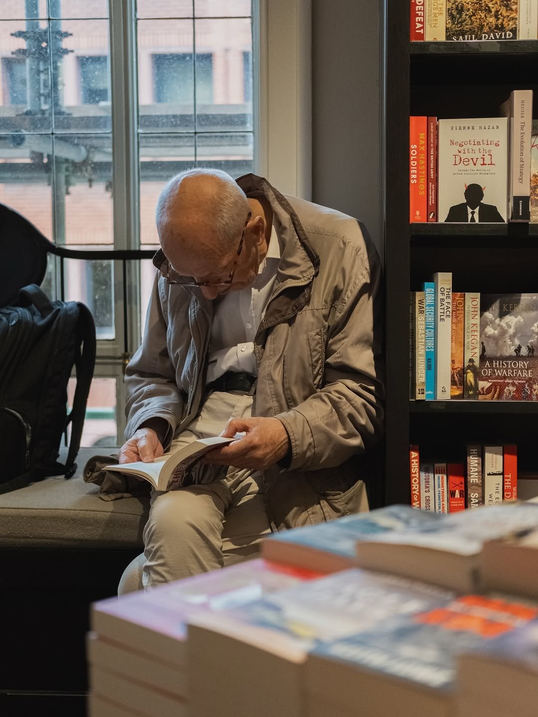 Man reading a book by bookshop window
