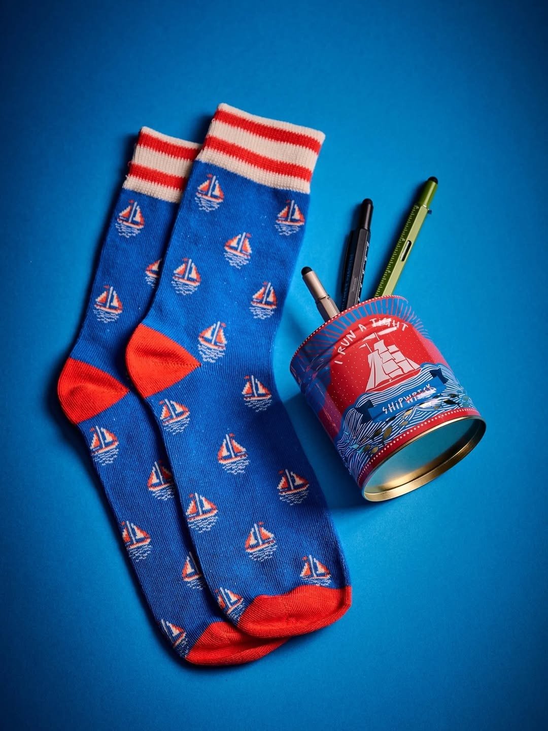 Blue novelty sailboat socks beside patterned tin