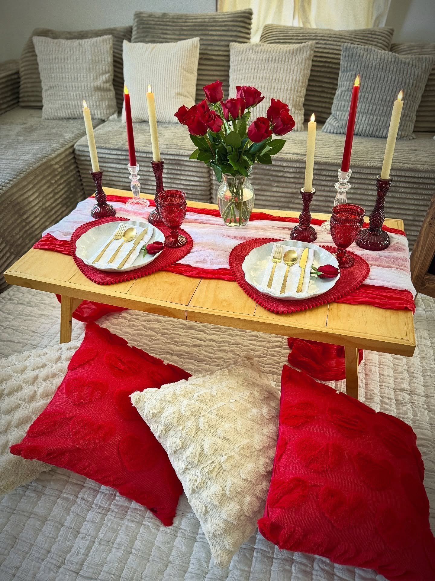Low wooden table with candles, red roses and floor pillows set, from our indoor picnic ideas guide