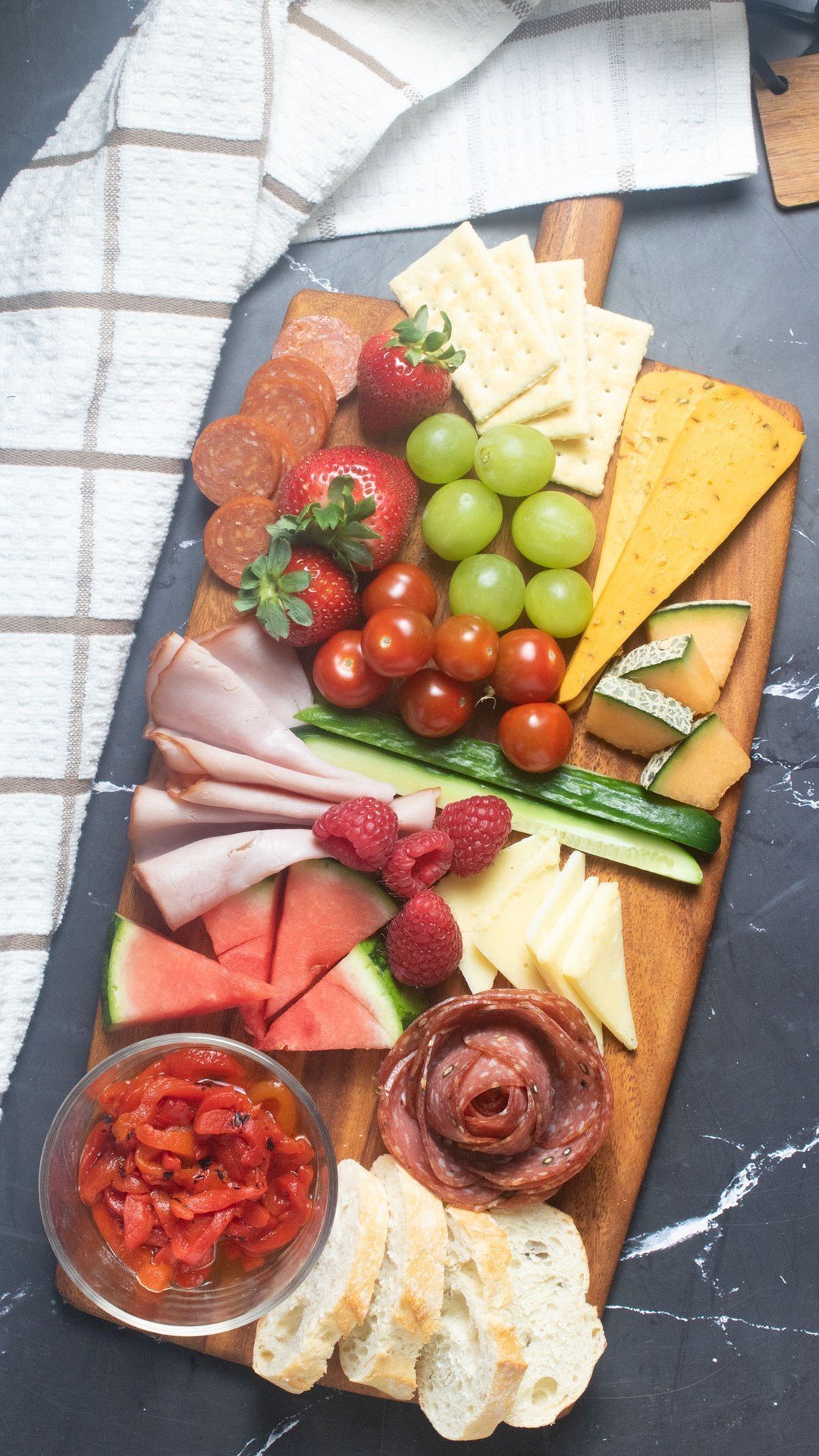 Overhead view of charcuterie board with meats, cheeses, fruit and crackers