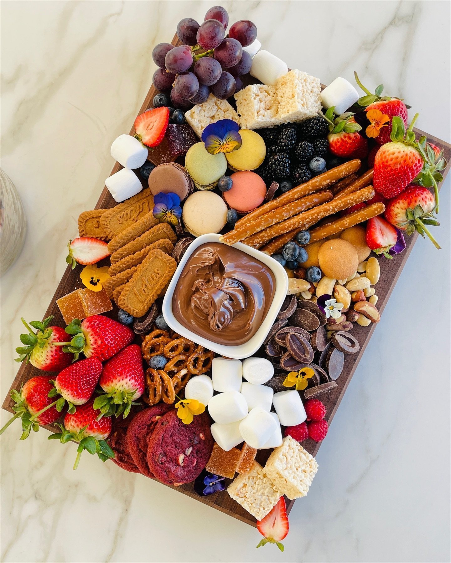 Dessert board with chocolate dip, strawberries, cookies and macarons