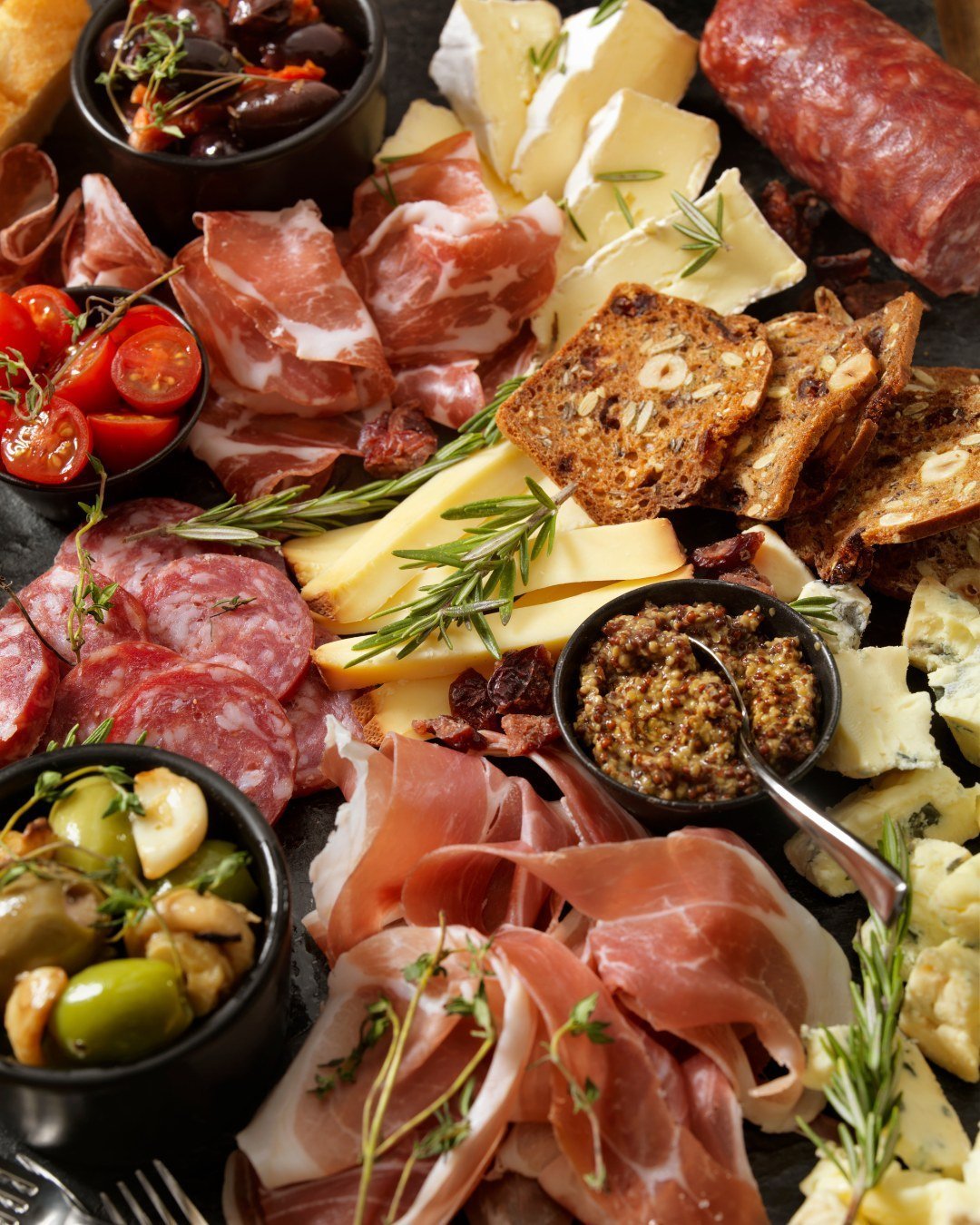 Overhead Italian spread with prosciutto, cheeses, olives and crackers