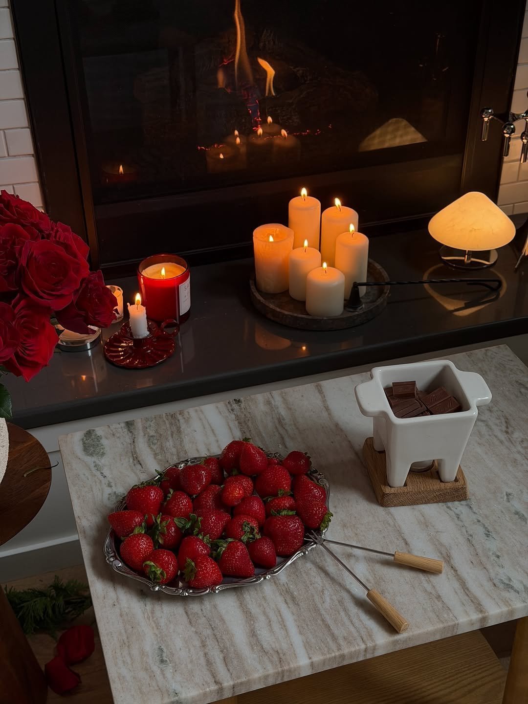 Chocolate fondue pot with strawberry platter by a fireplace