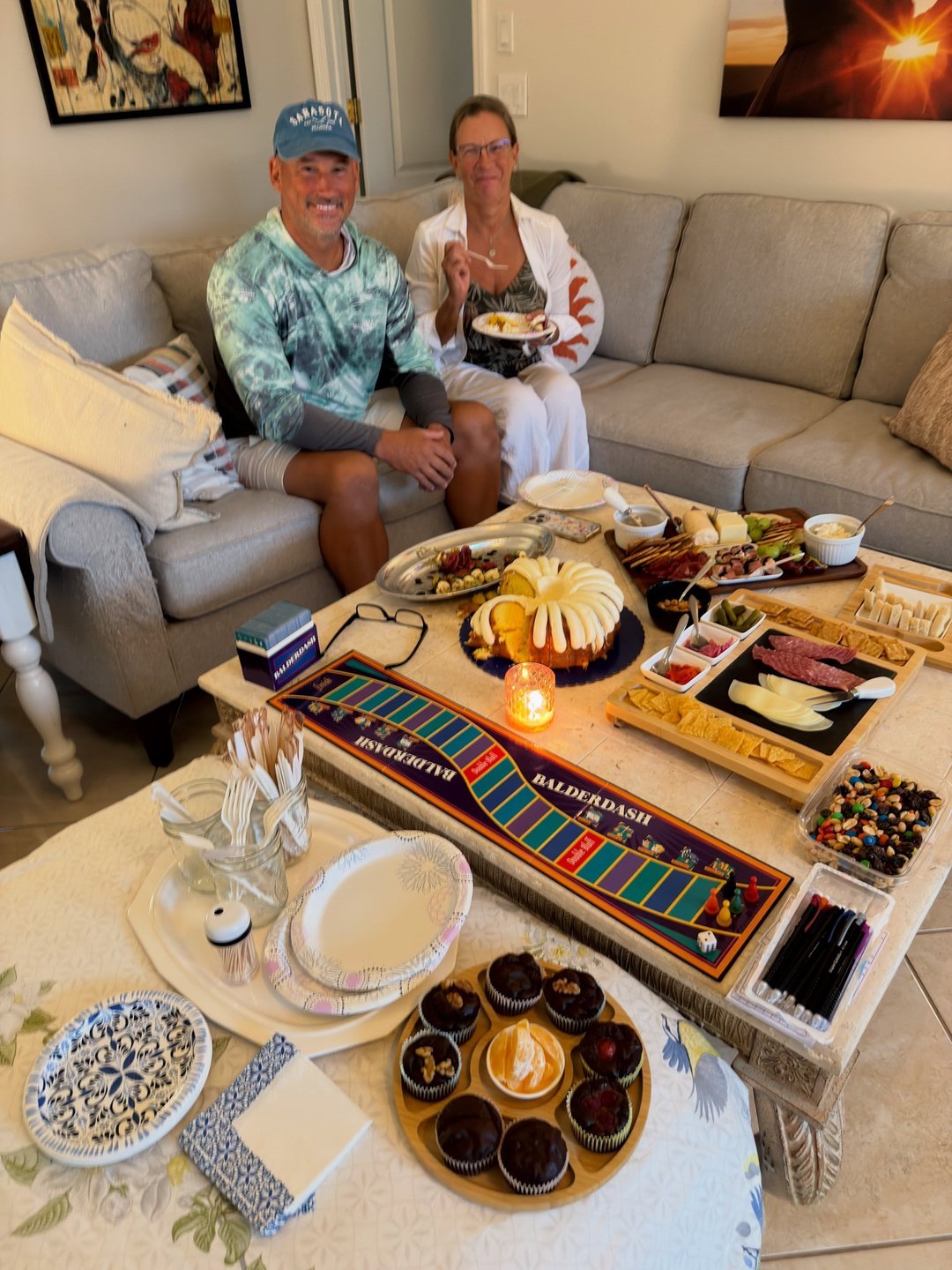 Couple with board game and snack boards on a living room table