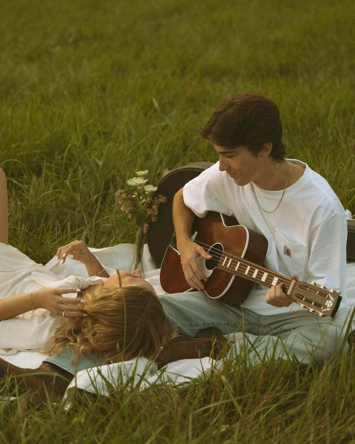 Couple on a picnic blanket with acoustic guitar in golden light