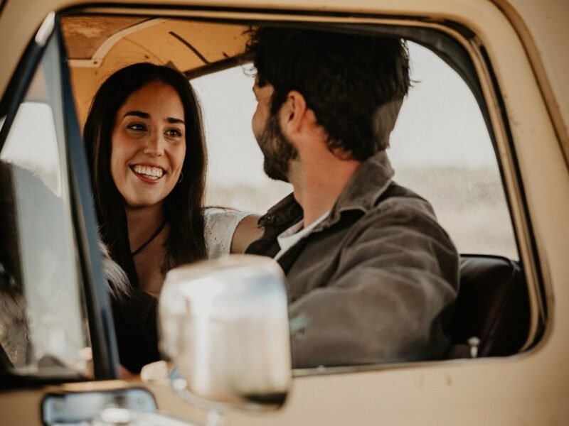 Couple laughing together inside a pickup truck cab, mid-conversation