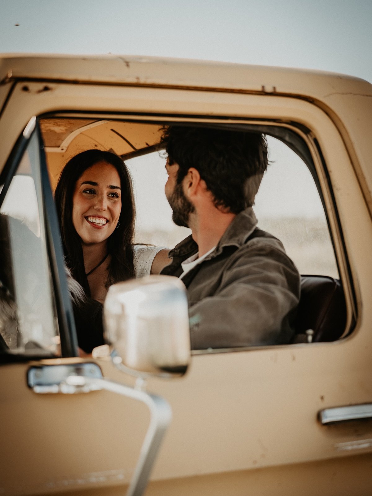 Couple laughing together inside a pickup truck cab, from our deep questions for couples guide
