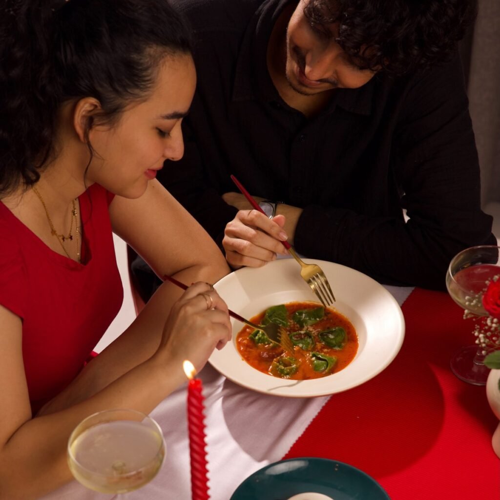 Couple sharing a meal at a candlelit dinner table at home