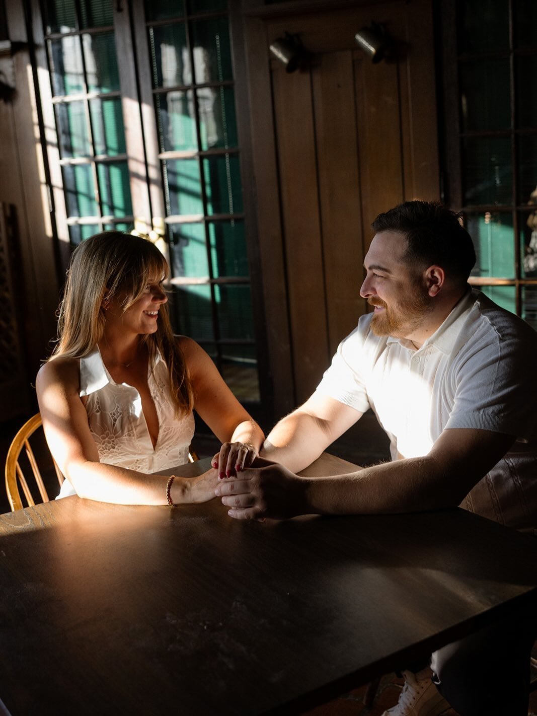 Couple holding hands across a table, leaning toward each other