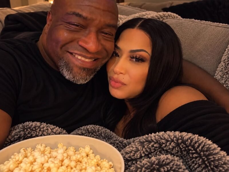 Couple cuddling on a couch holding a big bowl of popcorn under a cozy blanket