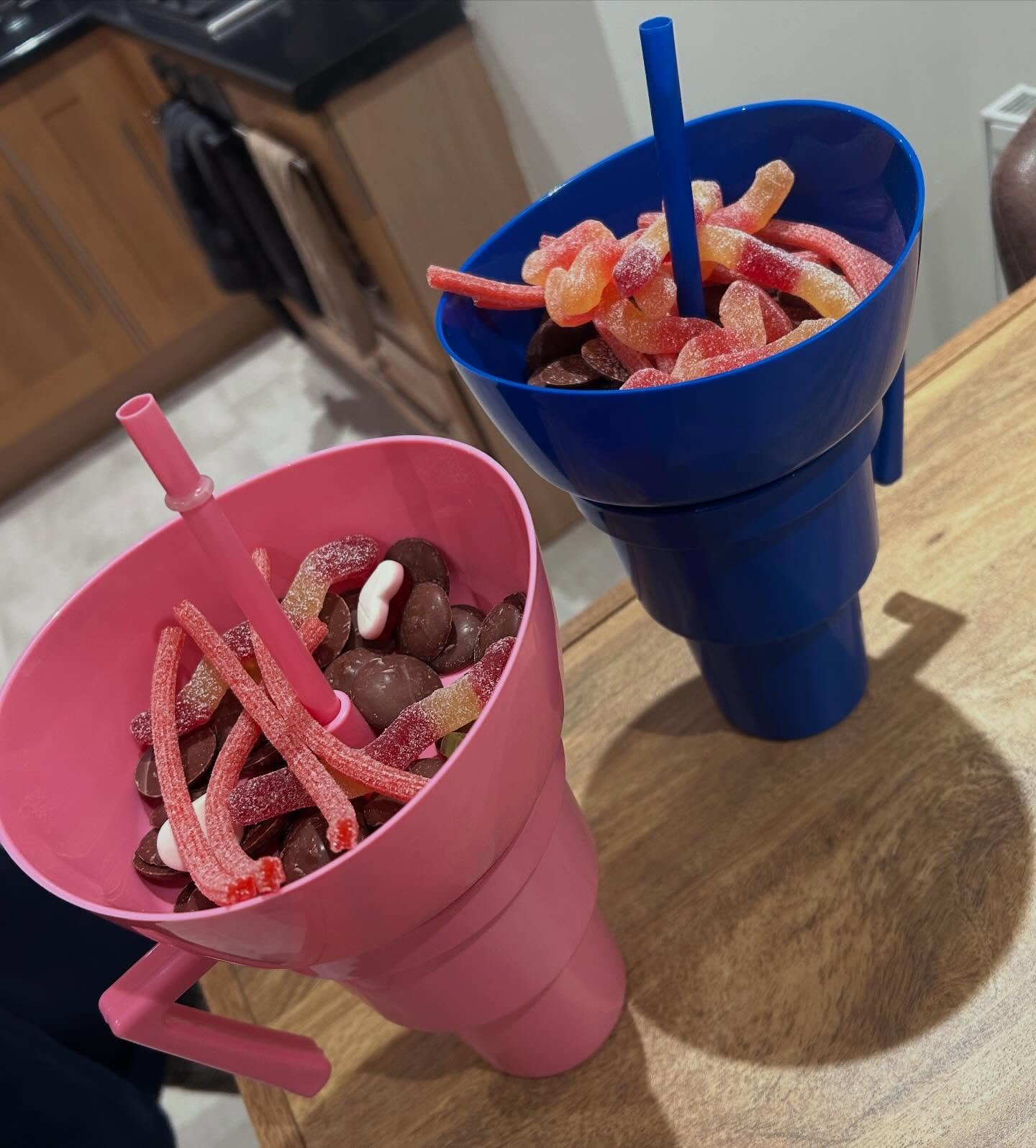 Two movie night cups filled with chocolate and sour sweets