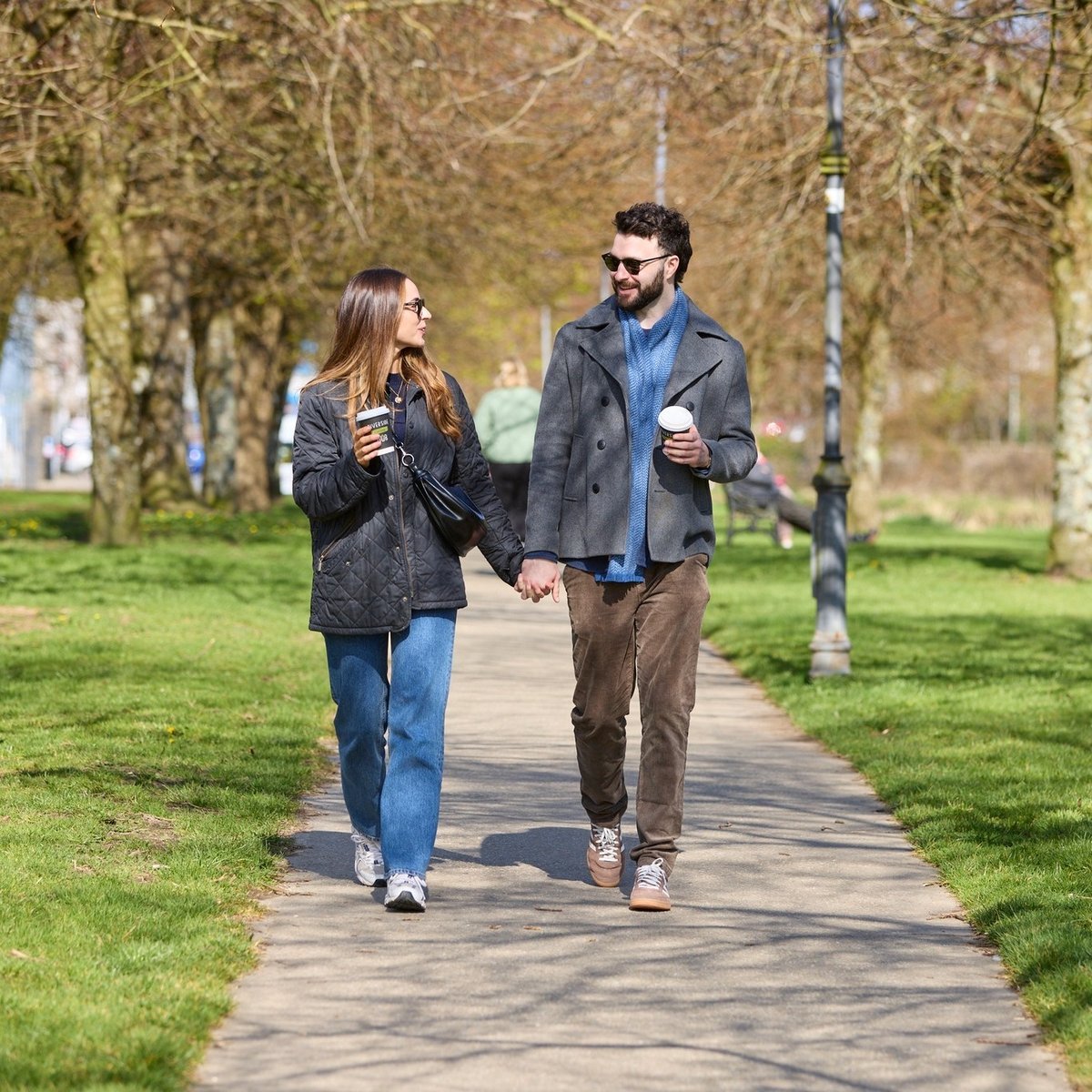Couple on a walk in the park holding coffee cups
