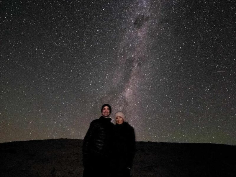 Couple standing under a starry night sky with the Milky Way above