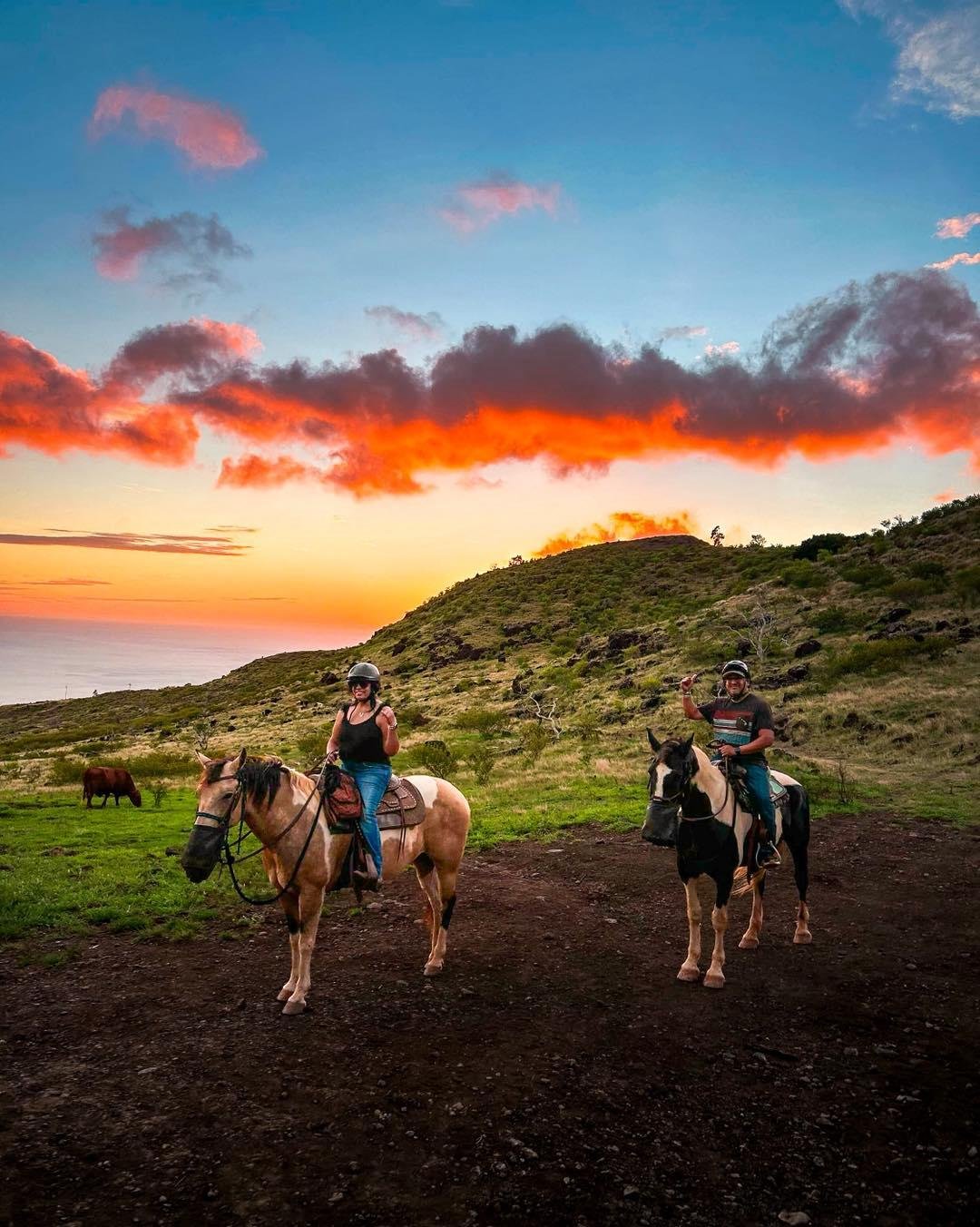 Couple on horseback on a mountain trail at sunset