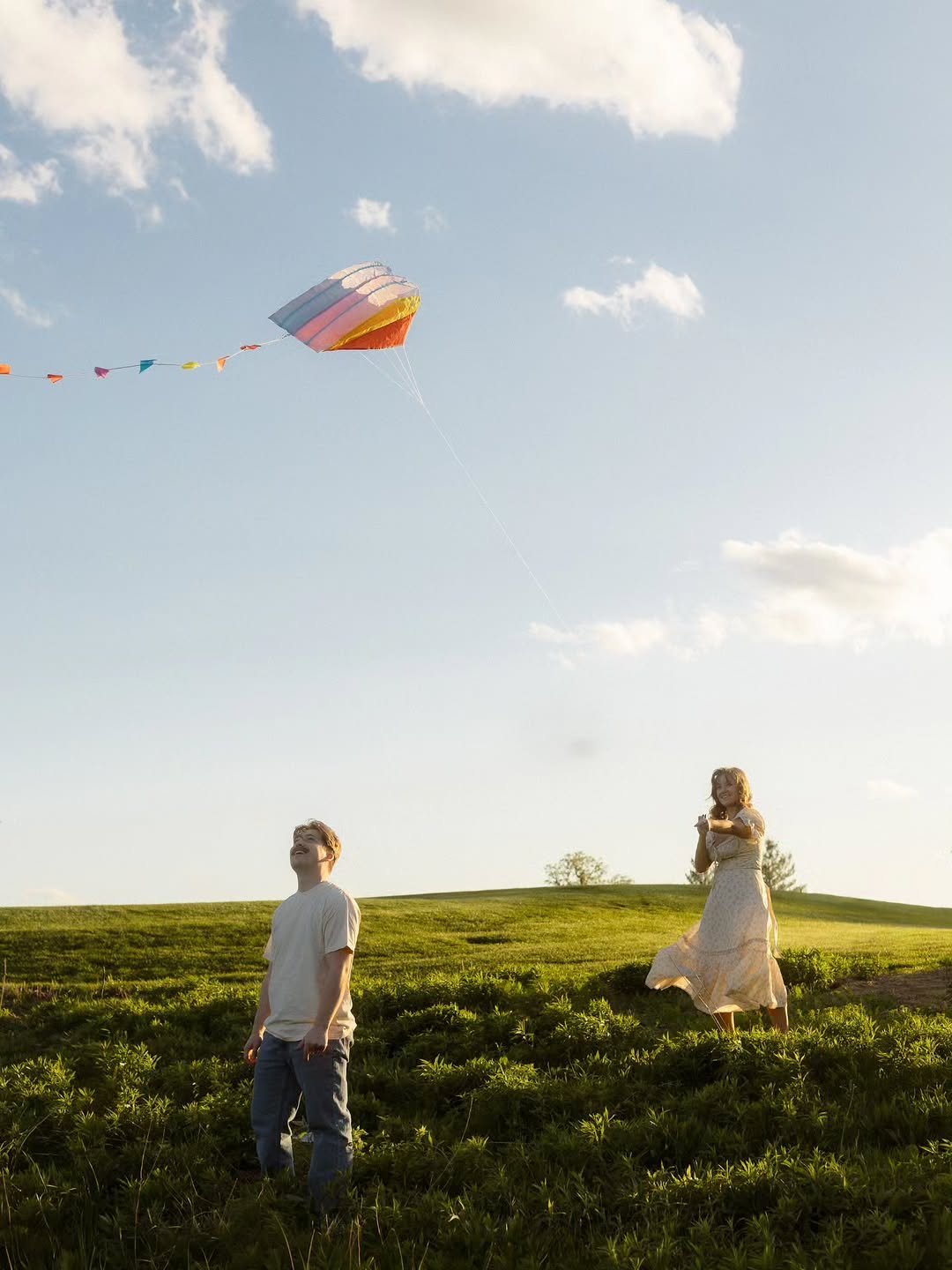 Woman flying a colorful kite in a field at golden hour