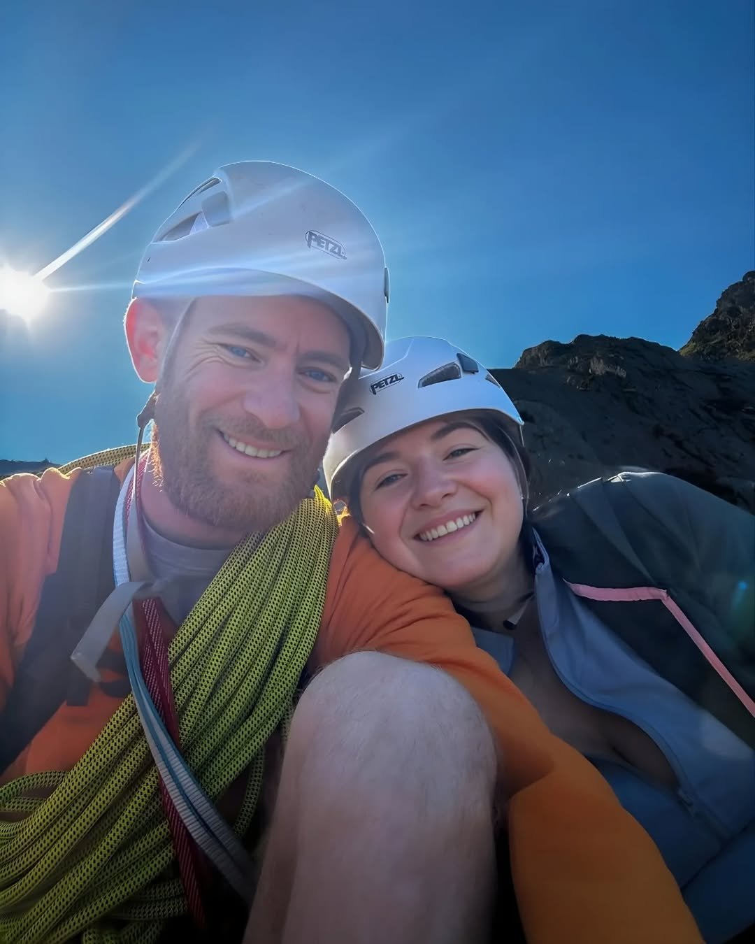 Climbing couple in helmets taking a selfie at a cliff