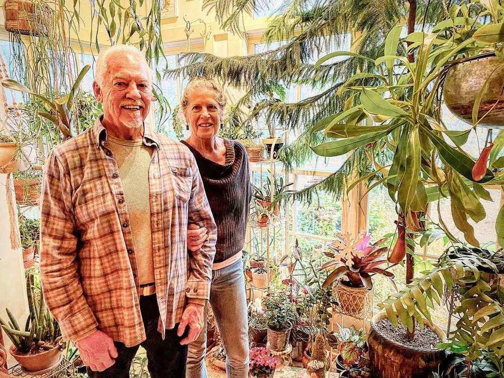 Older couple smiling among houseplants in a greenhouse