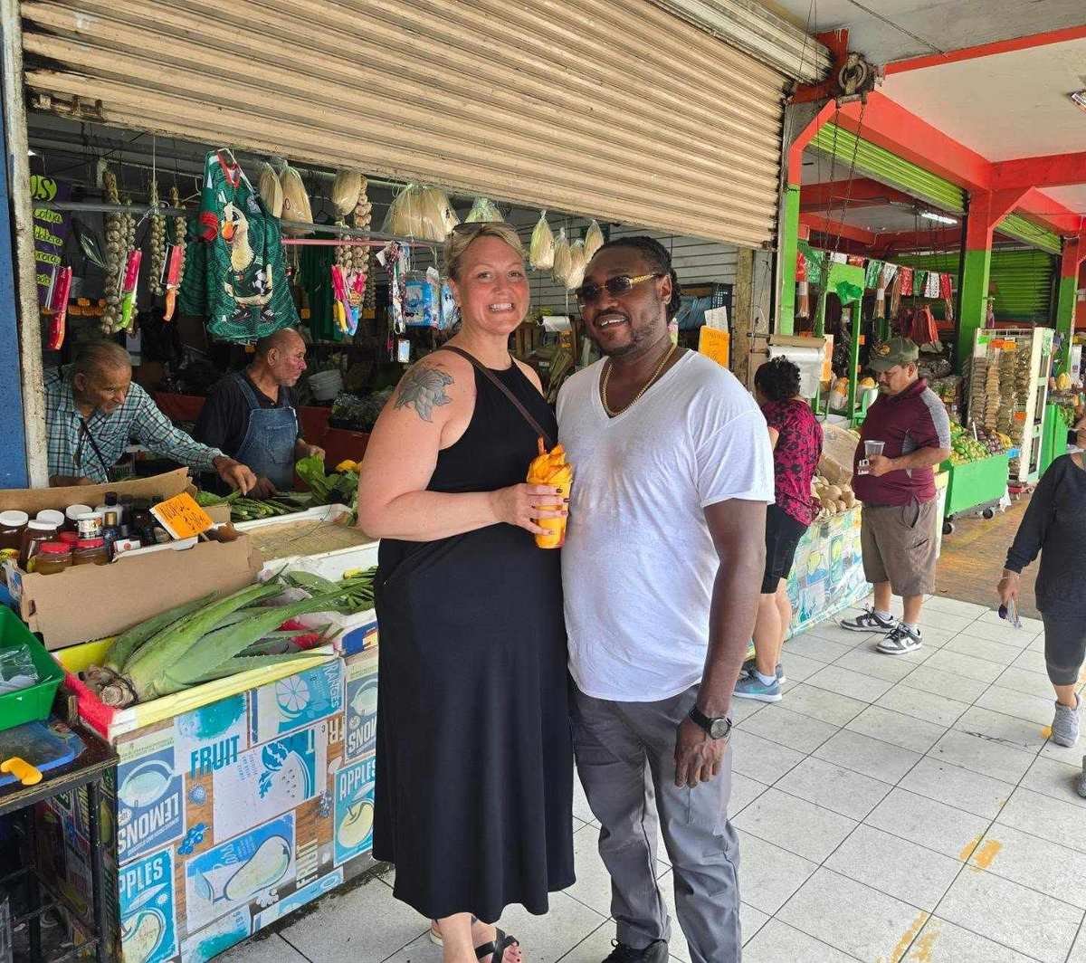 Couple posing with fresh mango at an outdoor market stall
