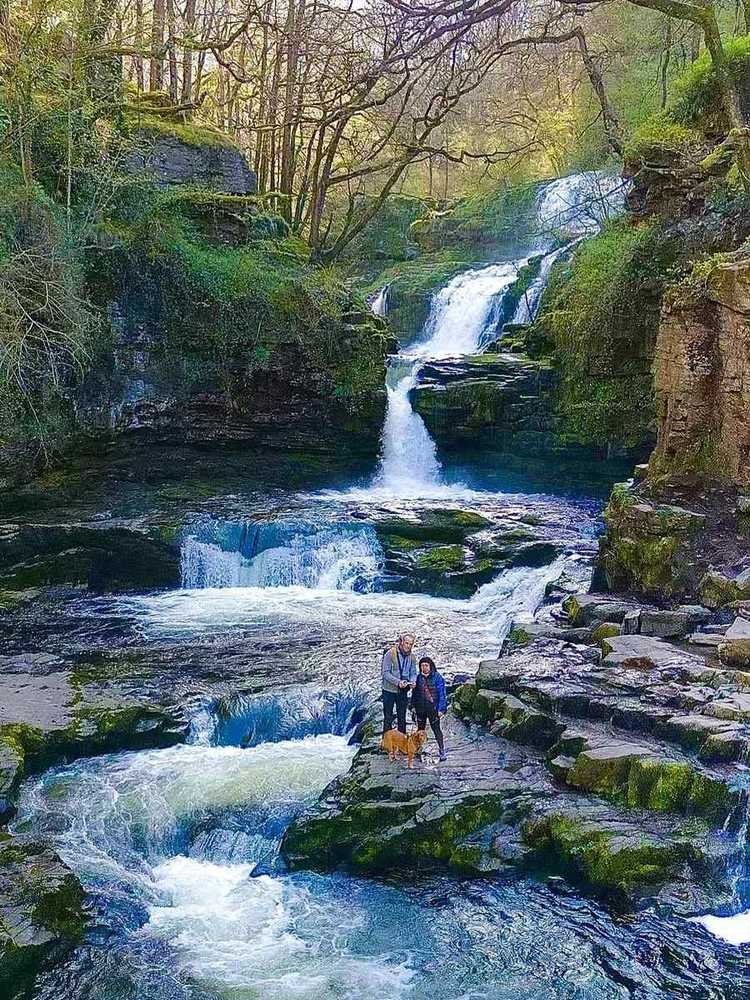 Couple and their dog at the base of a waterfall