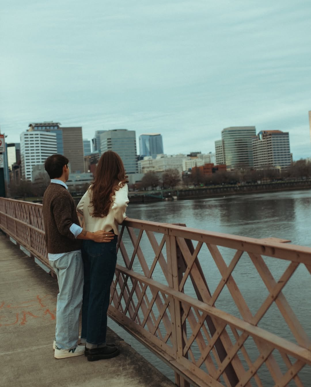 Couple embracing on a bridge during a waterfront evening stroll