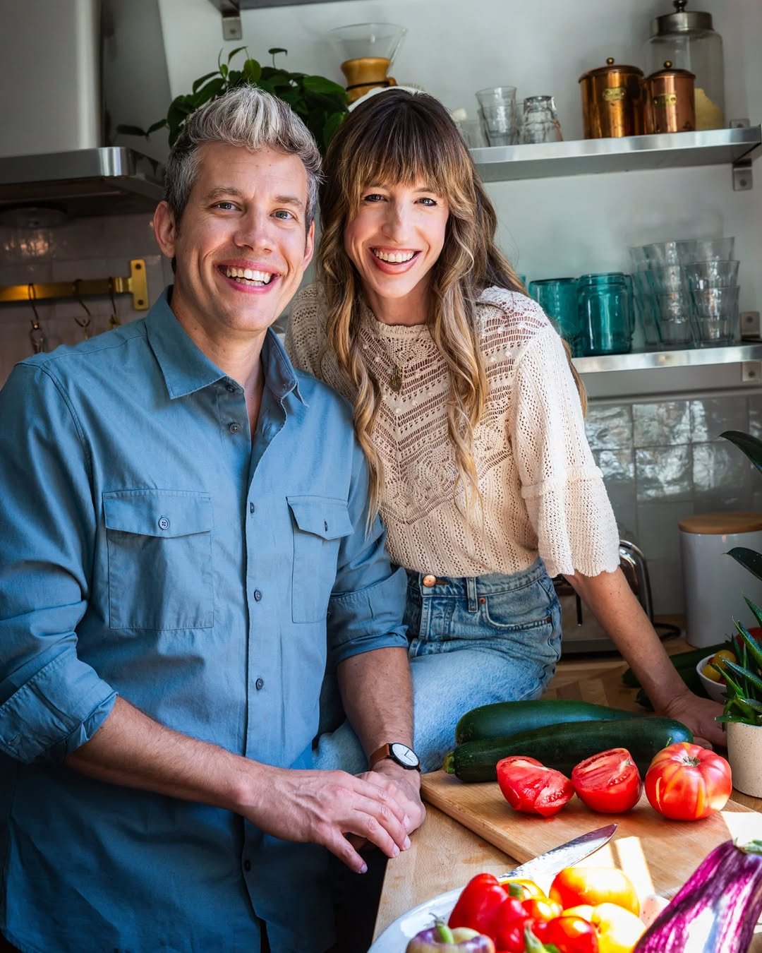 Couple smiling together in kitchen with fresh vegetables, about to cook