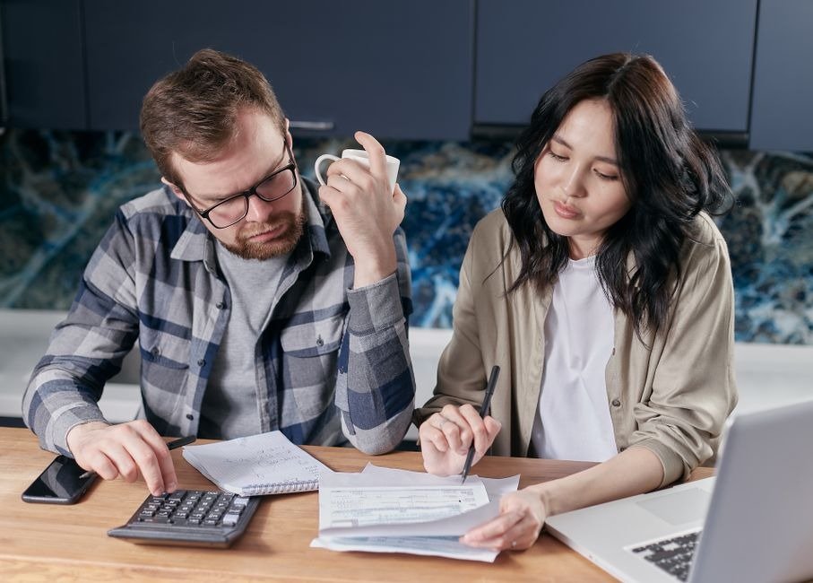 Couple reviewing bills at kitchen table with calculator, from our gift for your partner guide
