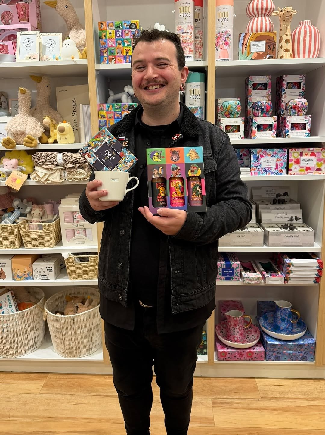 Man in gift shop holding up two gift options