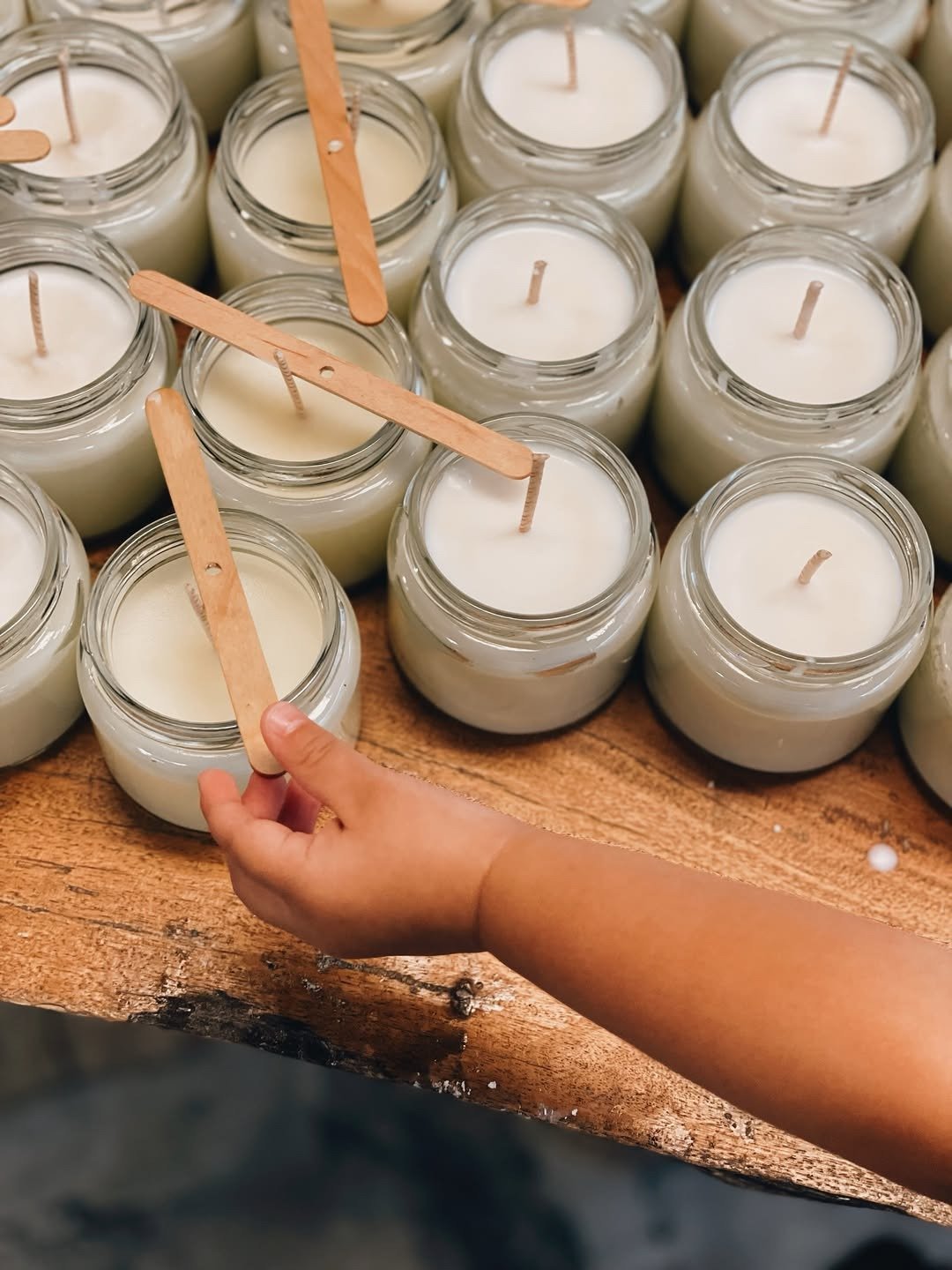 Hand pouring handmade candles in glass jars
