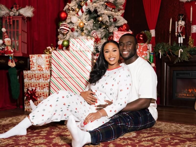 Newlywed couple in Christmas pyjamas beside stack of wrapped presents