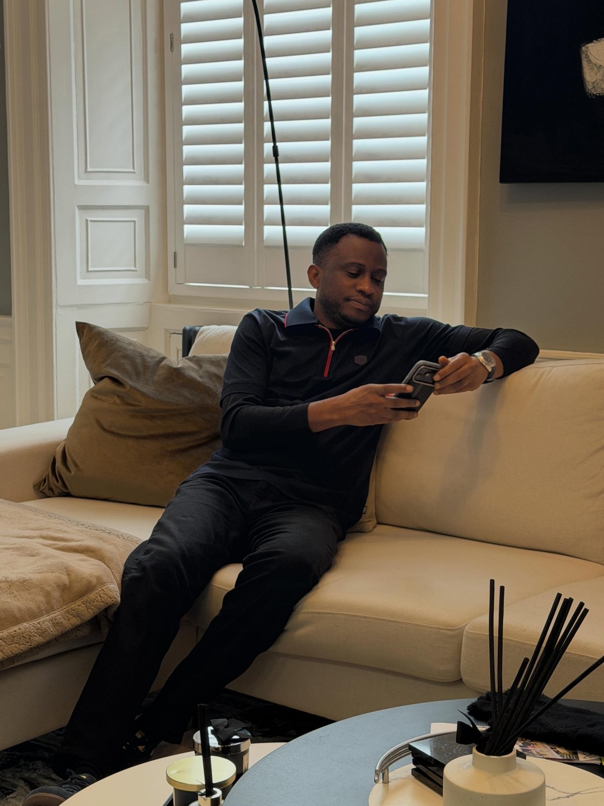 Man on a couch at home smiling while looking at his phone