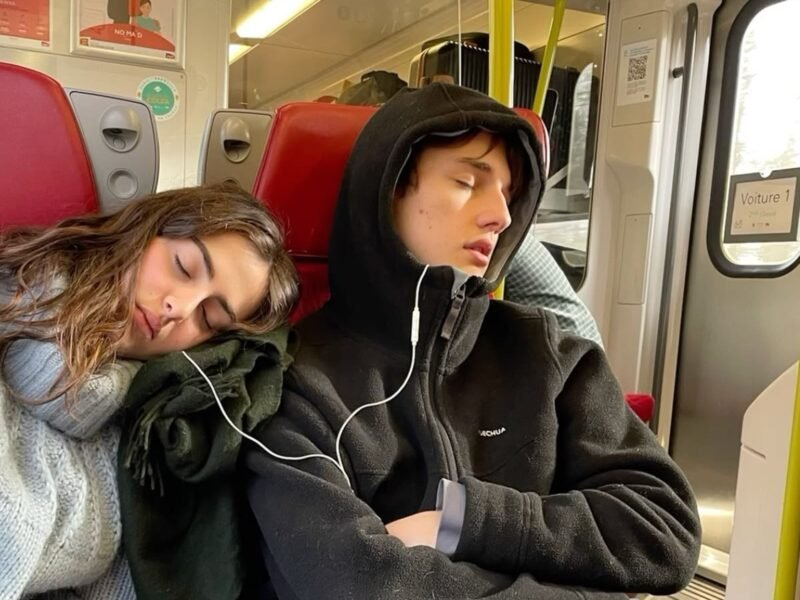 Couple napping on train seats sharing earphones