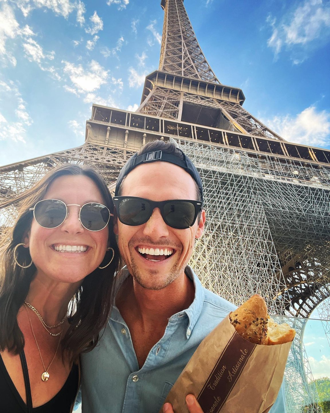Smiling couple taking a tourist selfie in front of the Eiffel Tower