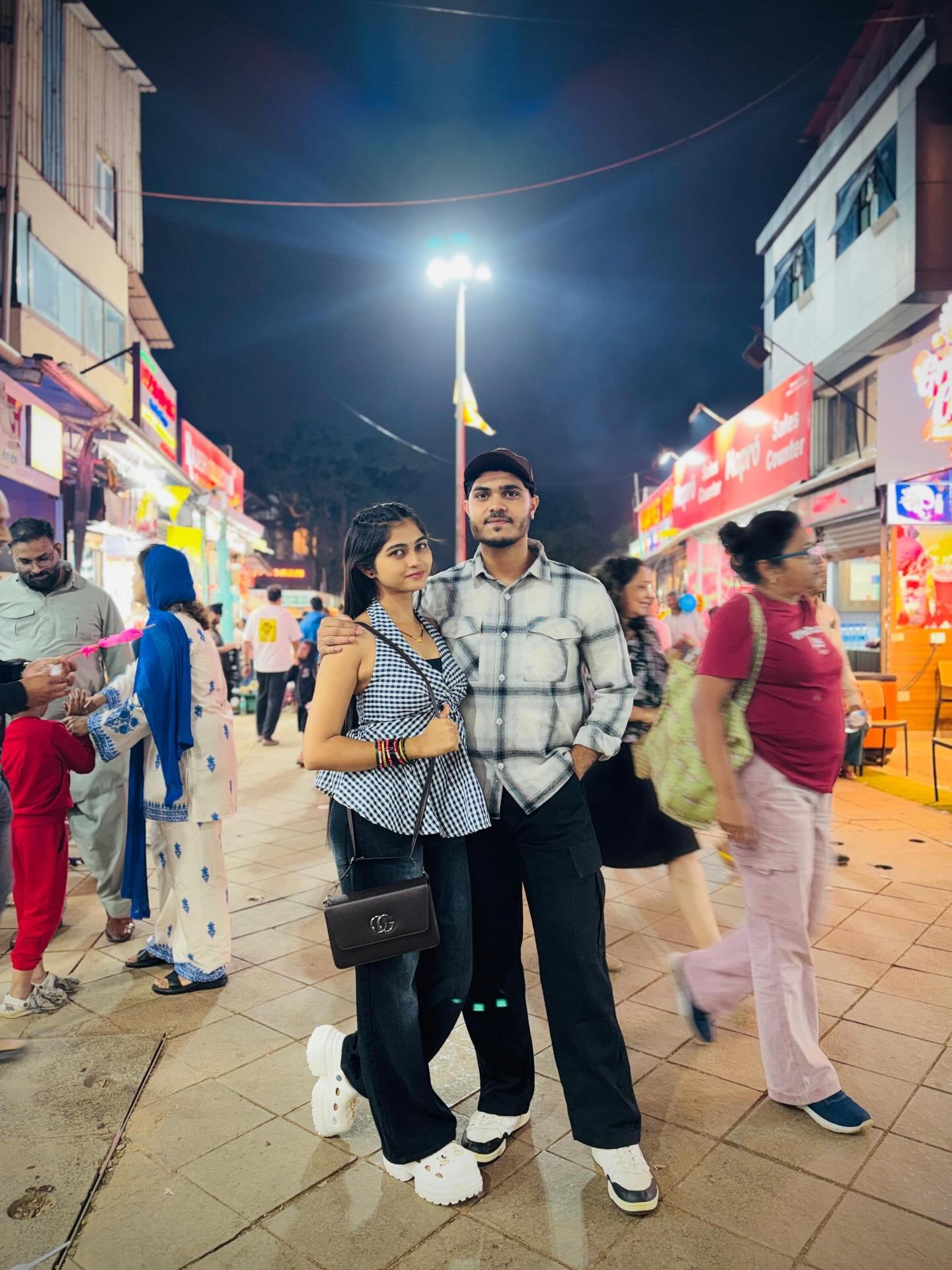 Couple posing at a night market with lit stalls