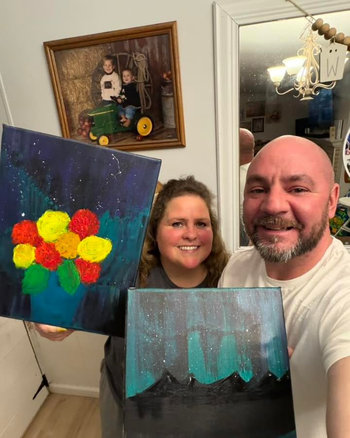 Couple holding up finished paintings