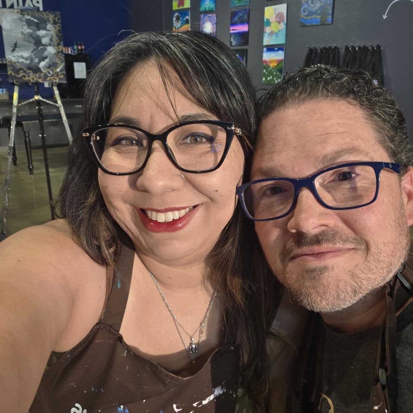 Couple in paint splattered aprons at paint night