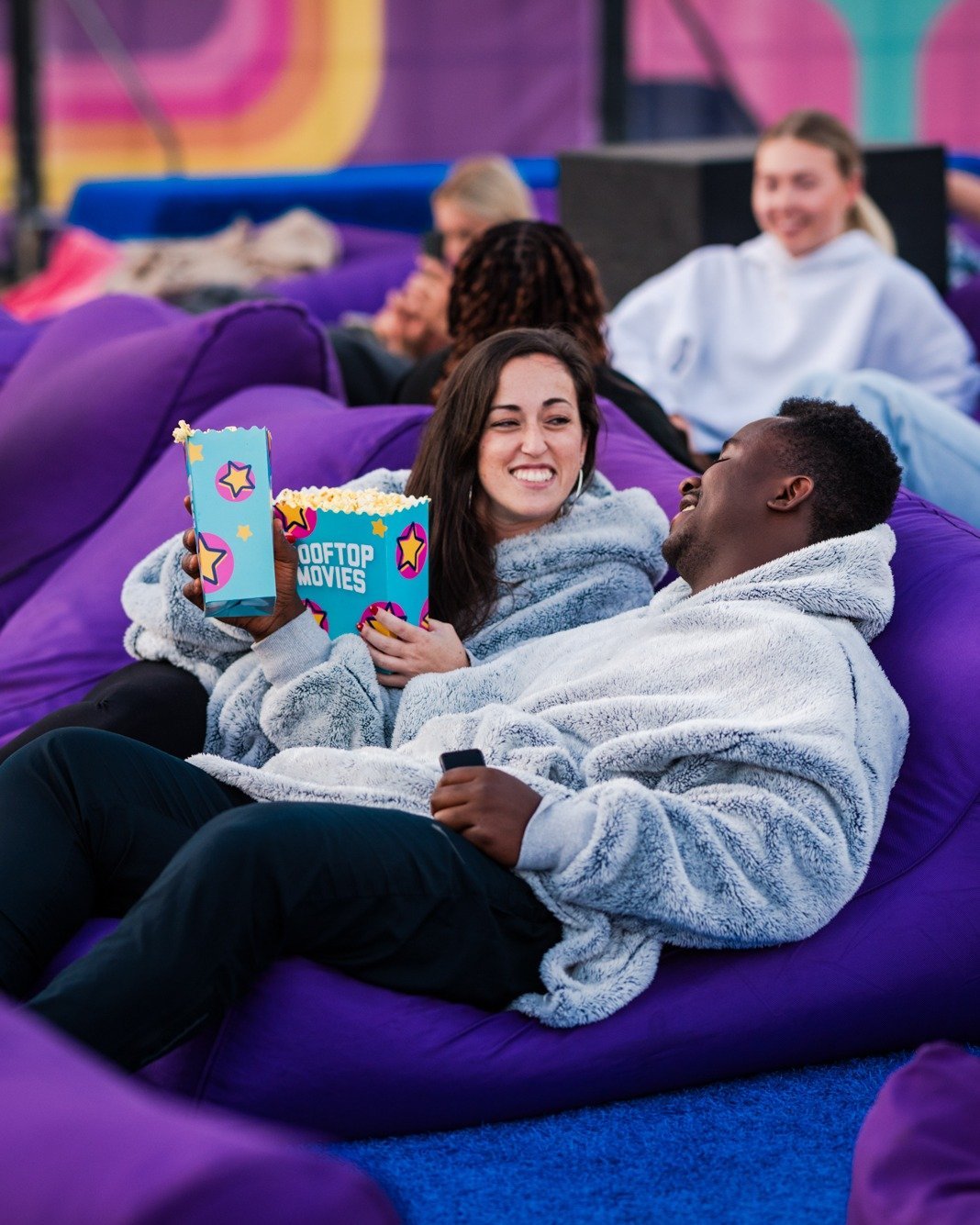 Couple on a beanbag at an outdoor rooftop cinema with popcorn