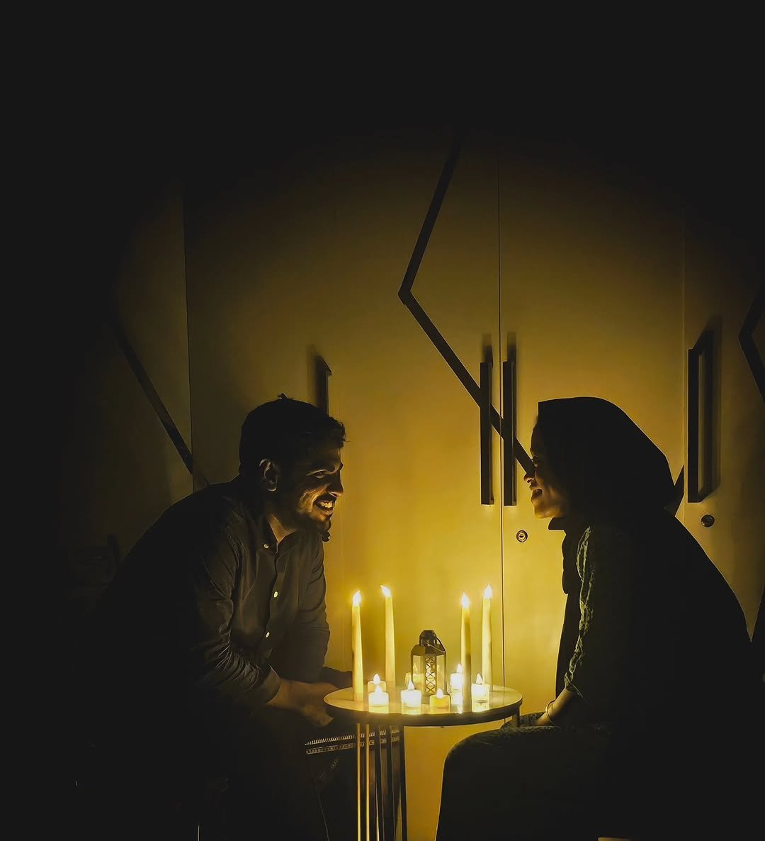 Couple at a small candlelit table at home, dark room, from our valentine's day date ideas guide