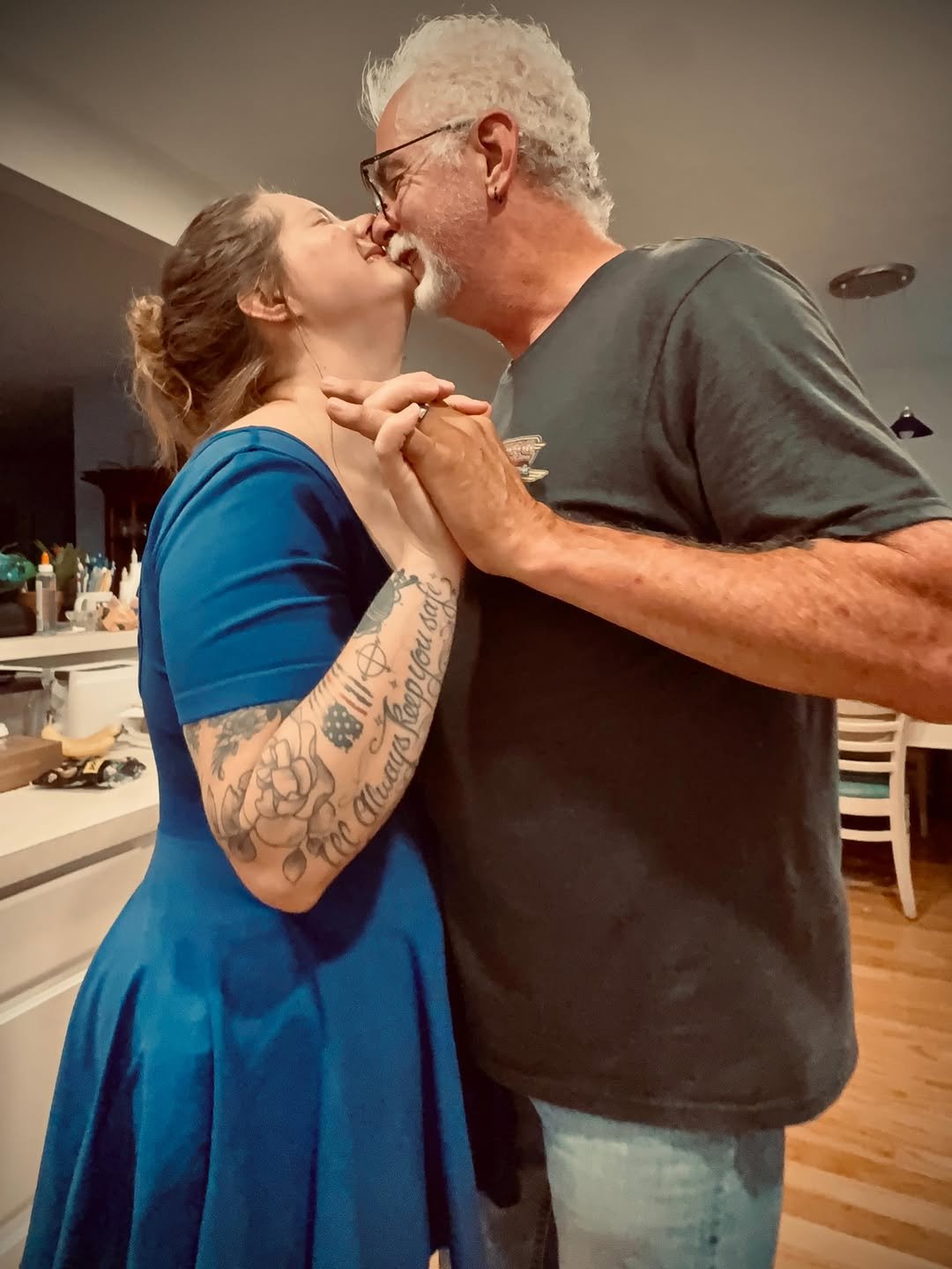 Couple slow dancing in their kitchen, woman in a blue dress