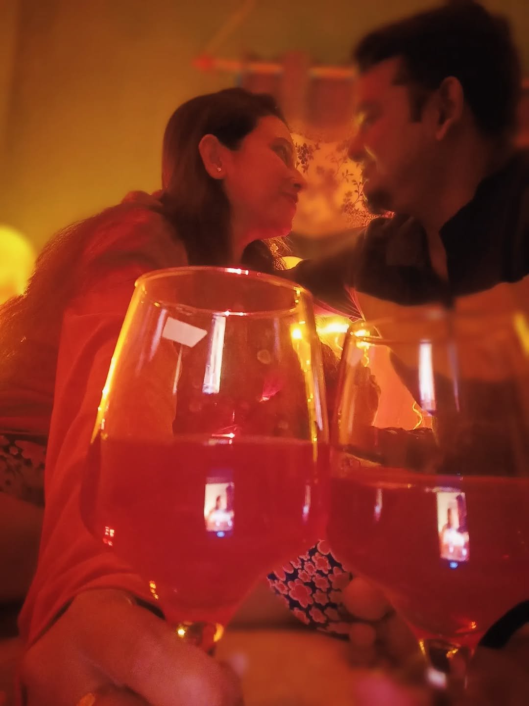 Couple toasting wine glasses with red wine in warm home lighting