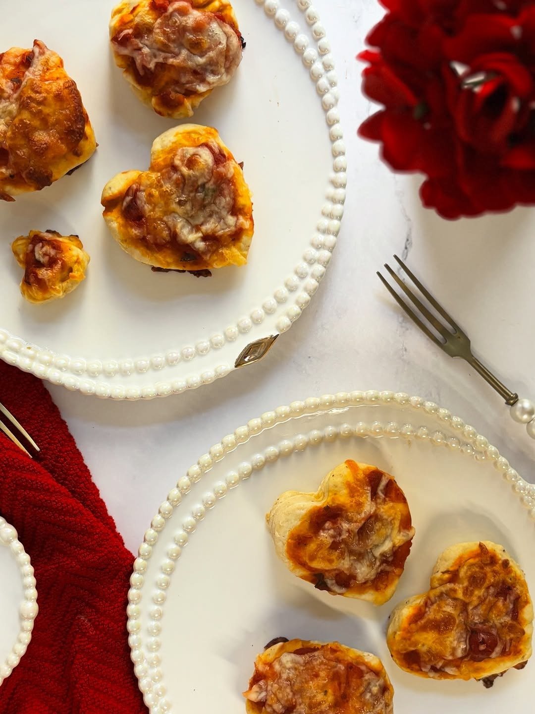 Heart-shaped mini pizzas on plates with a rose