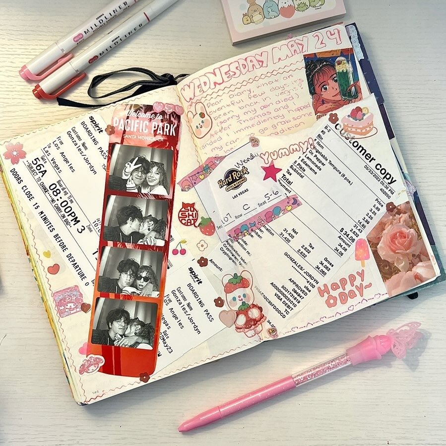 Open handwritten couples journal with pens and photo strips