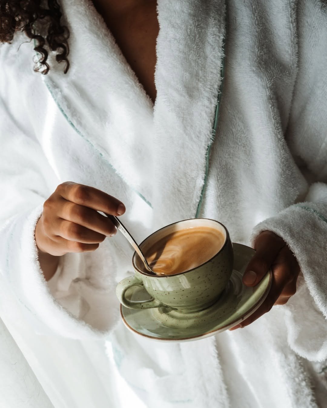 Woman in plush spa robe holding coffee