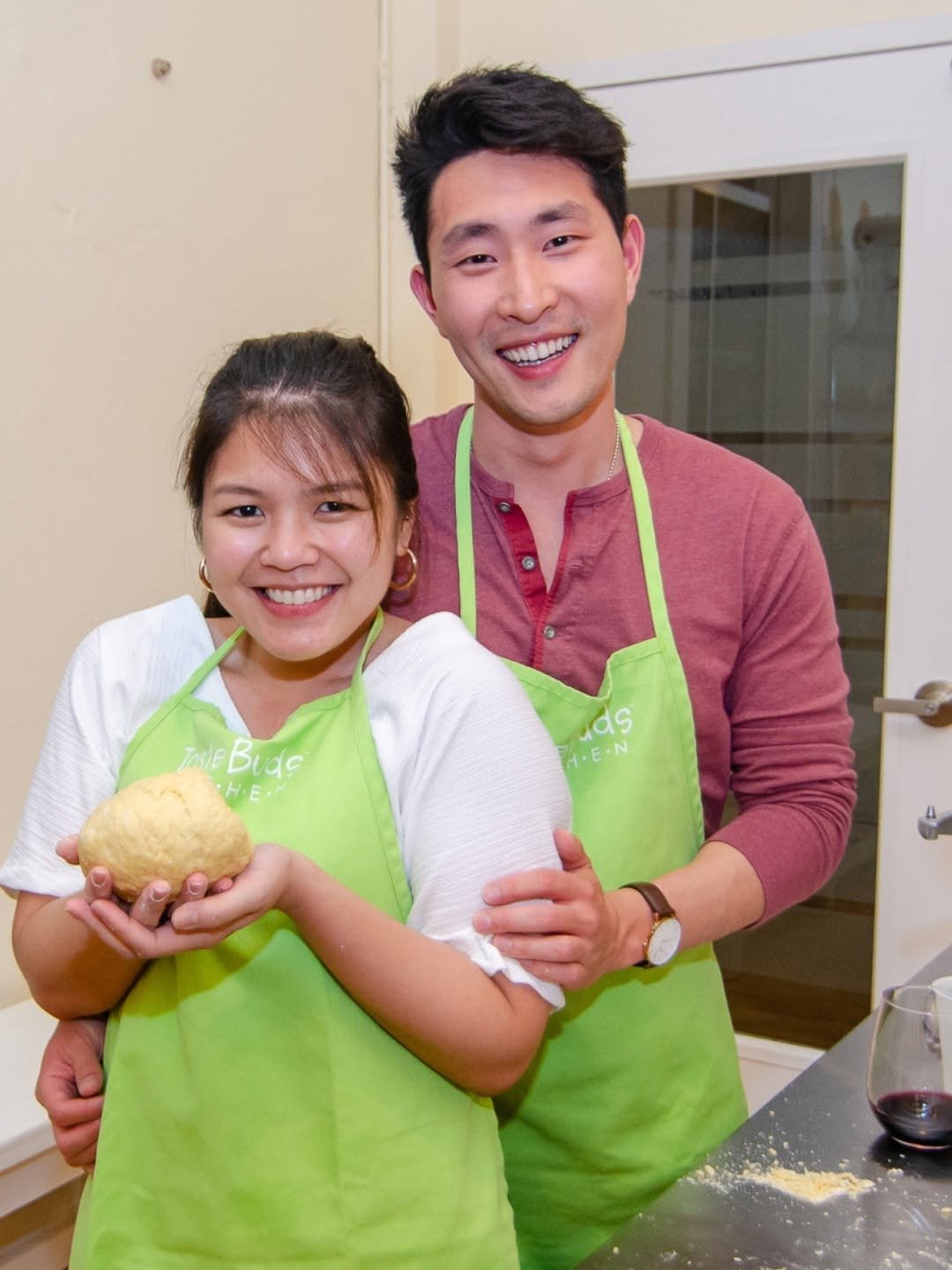 Couple in green aprons holding dough at cooking class