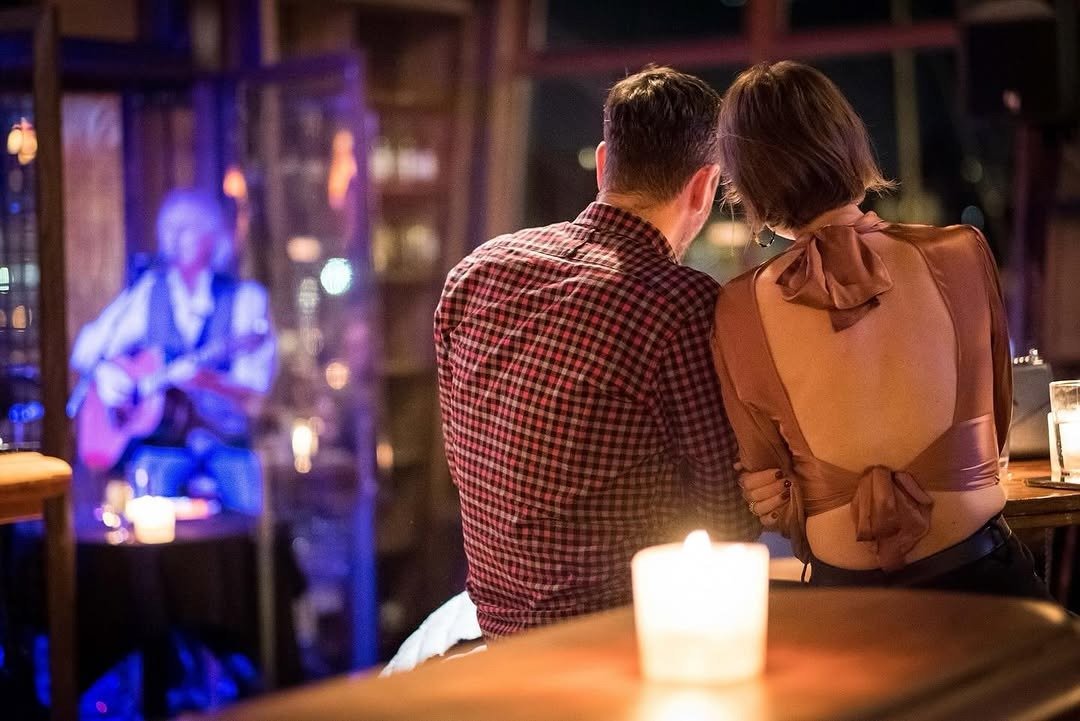 Couple watching live guitarist at candlelit table