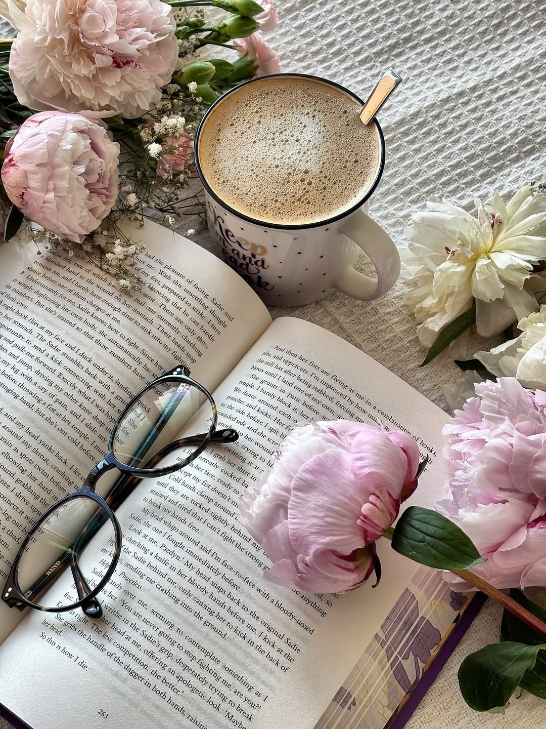 Open hardcover book with peonies and coffee flat lay