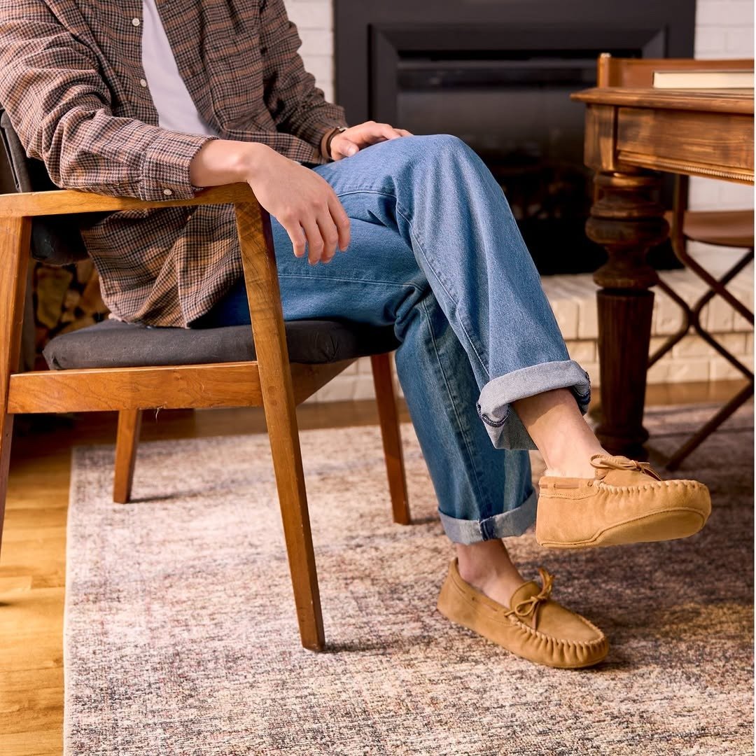 Man wearing sheepskin slippers by a fireplace