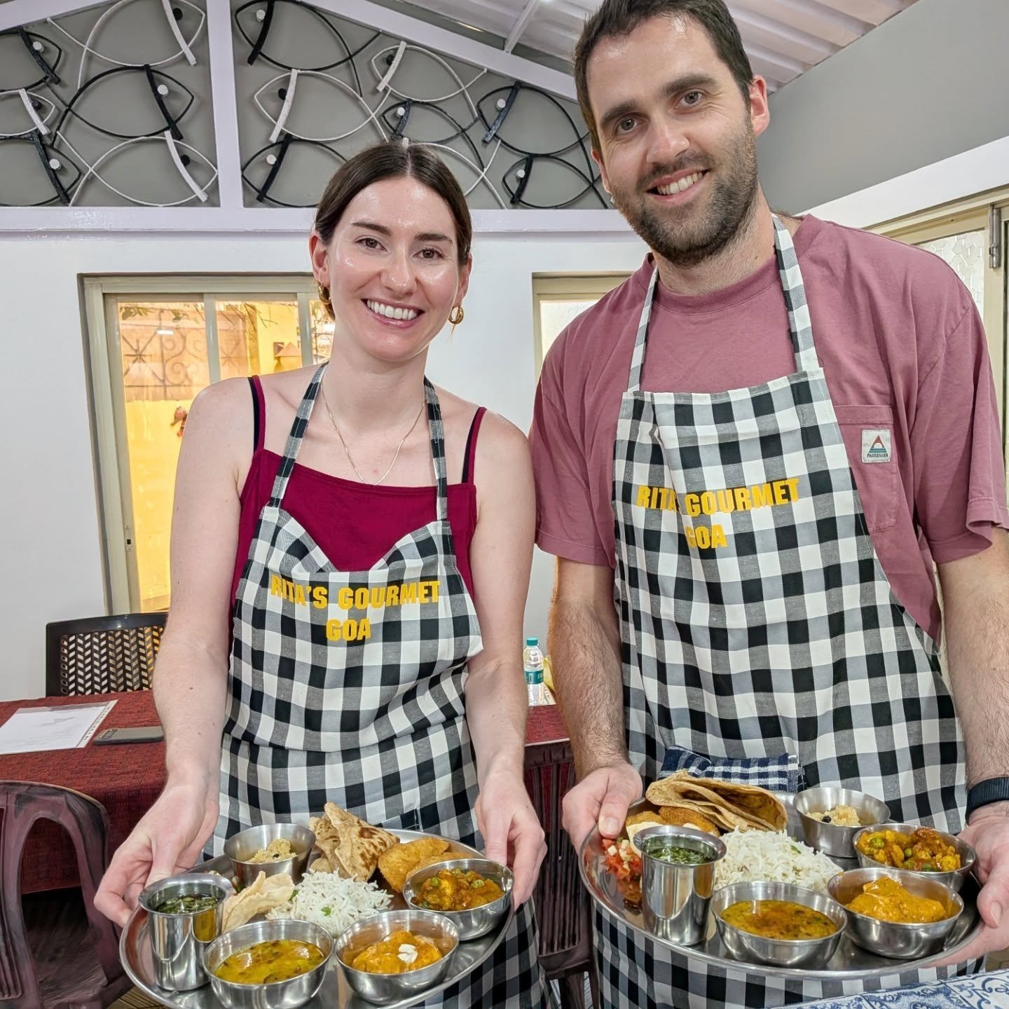 Couple in aprons holding food trays in cooking class